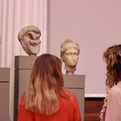 Two young women looking at sculptural heads in the museum